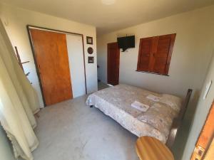 a small bedroom with a bed and a wooden door at Morro Beach Itarema in Itarema