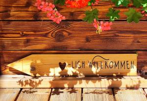 a sign on a wooden wall with flowers on it at Villa Bischofsberg - Lärchen-Wellness Apartment in Windischgarsten