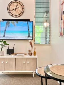 a living room with a tv and a clock on a wall at Tranquil treetop retreat minutes from the beach 7405 in Noosa Heads