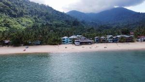 a beach with a group of houses and the water at Pondok Beach Shack in Tioman Island