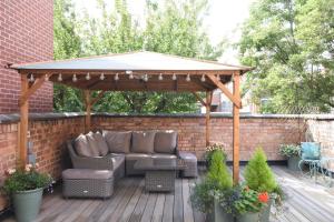 a wooden gazebo with a couch and table on a deck at The Hop Merchant's House in Worcester