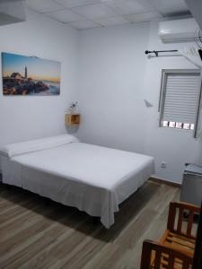 ein weißes Schlafzimmer mit einem großen Bett und 2 Stühlen in der Unterkunft Habitaciones Turísticas - La Tarayuela in Barbate