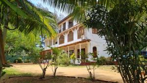 une maison blanche avec des arbres devant elle dans l'établissement Bohemian Lake, à Hambantota