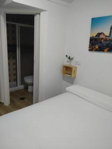 a white bedroom with a bed and a bathroom at Habitaciones Turísticas - La Tarayuela in Barbate
