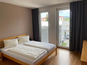 ein Schlafzimmer mit einem Bett und einem großen Fenster in der Unterkunft JD Apartment in Liptovský Mikuláš