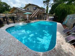 une grande piscine bleue avec des chaises en face d'une maison dans l'établissement Pool-Spacious, Main House Haven, à Pensacola