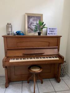 a piano in a room with a picture and a stool at Burgerwoning bij Brugge in Bruges