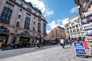 ロンドンにあるGrandeur 3 Bedroom Flat in London, Mayfair HY3の建物や人乗り自転車が並ぶ賑やかな街道