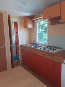 a kitchen with red cabinets and a sink and a window at Mobilhome Vue mer et nature in Plougastel-Daoulas