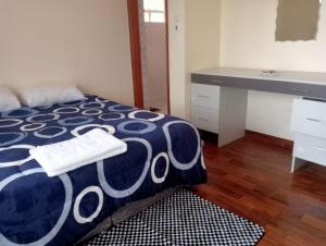 een slaapkamer met een blauw en wit bed en een bureau bij BomaBnB Holiday Homes in Nairobi