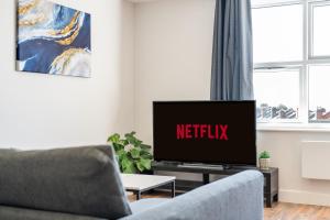 a living room with a television with the netflix sign on it at 4 West London Brand New Loft in London