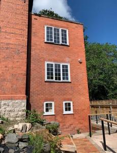 a red brick building with three windows on it at Netherton Studio Apartment 2 in Llandrillo-yn-Rhôs