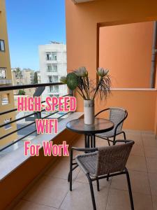 a table with chairs and a vase with flowers on a balcony at VIP Resort Apartment on Makenzie Beach in Larnaca