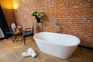 uma banheira branca num quarto com uma parede de tijolos em HOTEL TEATR em Cracóvia