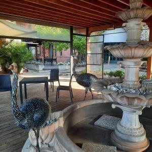 2 paons sur un patio à côté d'une fontaine dans l'établissement Segnavento -Rooms and Suites-, à Manta