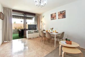 a living room with a table and chairs and a television at Exclusive 1 bedroom apartment with a Pool in Arona