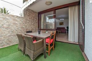 a patio with a table and chairs and a living room at Exclusive 1 bedroom apartment with a Pool in Arona
