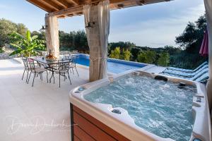 einen Whirlpool auf einer Terrasse mit einem Tisch und Stühlen in der Unterkunft Island Villa Adriana with heated pool and sauna in Lun