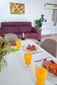 Exclusive 1 bedroom apartment with a Pool في أرونا: طاولة مع أطباق من الطعام وكؤوس من عصير البرتقال