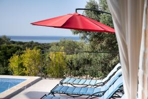 duas cadeiras e um guarda-sol vermelho numa piscina em Island Villa Adriana with heated pool and sauna em Lun