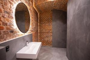 uma casa de banho com um lavatório branco e uma parede de tijolos em HOTEL TEATR em Cracóvia