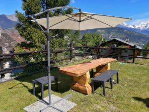 ein Holztisch und eine Bank mit einem Sonnenschirm in der Unterkunft Maison Cenne Vda Gressan n 0030 in Gressan