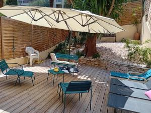una terraza de madera con sillas y sombrilla en NICE- GAIRAUT - JARDIN PRIVE- GRAND F1 LUMINEUX-Piscine Collective en Niza