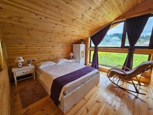 1 dormitorio con 1 cama, 1 silla y 1 ventana en La Căsuță en Vatra Dornei