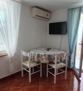 a table and chairs in a room with a tv at Apartments Maxim in Tivat