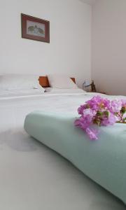a white bed with a bouquet of flowers on it at Apartments Maxim in Tivat