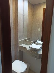 a bathroom with a toilet and a sink with a mirror at Loft Centro - No Calçadão e em frente Parque das Águas in São Lourenço