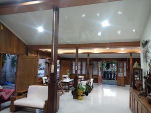 a living room with wooden walls and white furniture at Cahaya Losmen Sragen Syariah in Sragen +1 photo