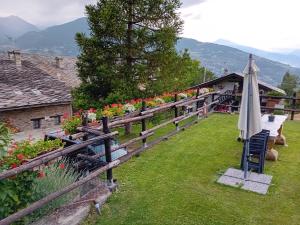 a fence with an umbrella and chairs and a house at Maison Perriail Vda Gressan n 0029 in Gressan