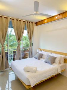 Schlafzimmer mit einem großen weißen Bett vor einem Fenster in der Unterkunft Dhoani Maldives Guesthouse in Kendhoo
