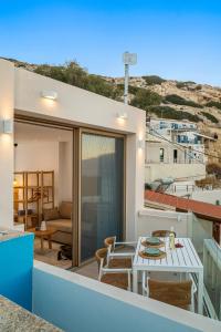 a balcony of a house with a table and chairs at LA MER Suite 2 in Matala