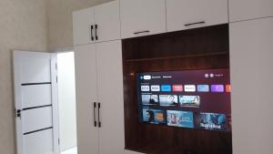 a kitchen with white cabinets and a flat screen tv at Begzod's house in Samarkand