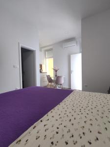 a bedroom with a purple bed and a table and chairs at Studio apartman Mara in Imotski