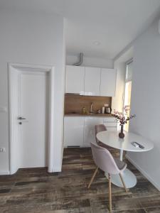a white kitchen with a table and a chair at Studio apartman Mara in Imotski
