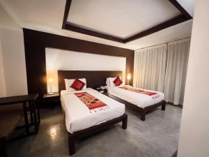 a hotel room with two beds and a desk at City Inn Vientiane in Vientiane