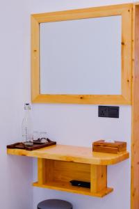 a mirror on top of a wooden table with a stool at Dhoani Maldives Guesthouse in Kendhoo