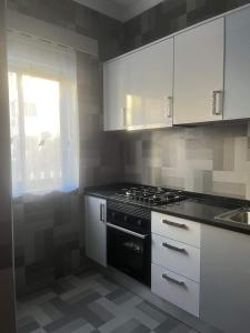 d'une cuisine avec des placards blancs, une cuisinière et une fenêtre. dans l'établissement Moreira's Apartment, à Praia