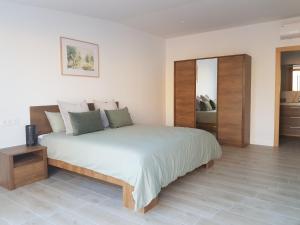 1 dormitorio con 1 cama blanca grande y espejo en VILLAMÓNICA, en Torrellano