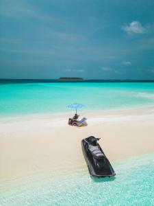 a boat sitting on a beach with an umbrella at Dhoani Maldives Guesthouse in Kendhoo