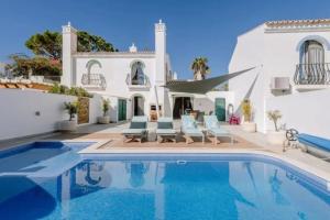 a villa with a swimming pool in front of a house at HÔTELS &ASPA in Estoril