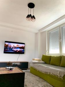 uma sala de estar com um sofá verde e uma televisão de ecrã plano em Lanada Apartment Skopje em Skopje