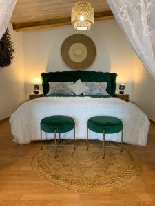 a bedroom with a bed with two green chairs at Lepetitcoinenchante in Saint-Louis