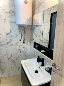 uma casa de banho com um lavatório branco e um espelho. em Lanada Apartment Skopje em Skopje