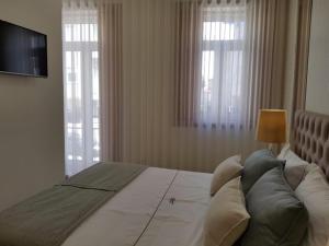 a bedroom with a large bed with a television and windows at HÔTELS &ASPA in Estoril