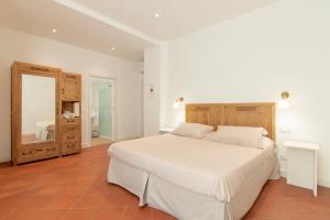 1 dormitorio con 1 cama blanca grande y espejo en B&B Villa Eden jacuzzi pool, en Domaso