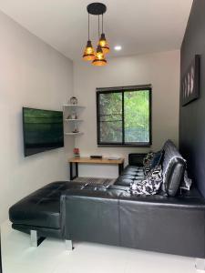 a black leather couch in a room with a table at Bonnie Baan Private Pool Villa, Mae Rim in Mae Rim